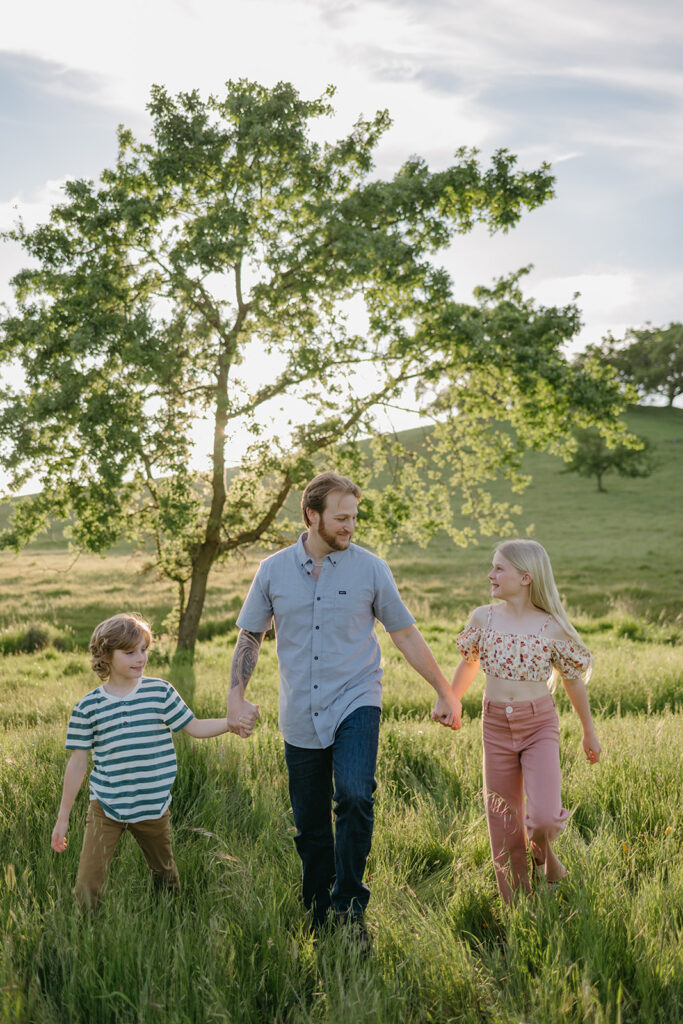 dad walking with children in an open field in novato